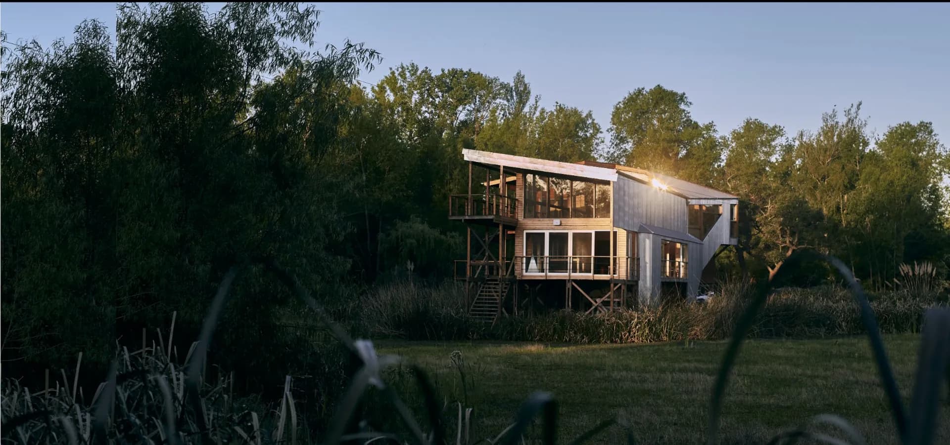 Una casa de madera sobre pilotes entre los árboles del Delta, al atardecer